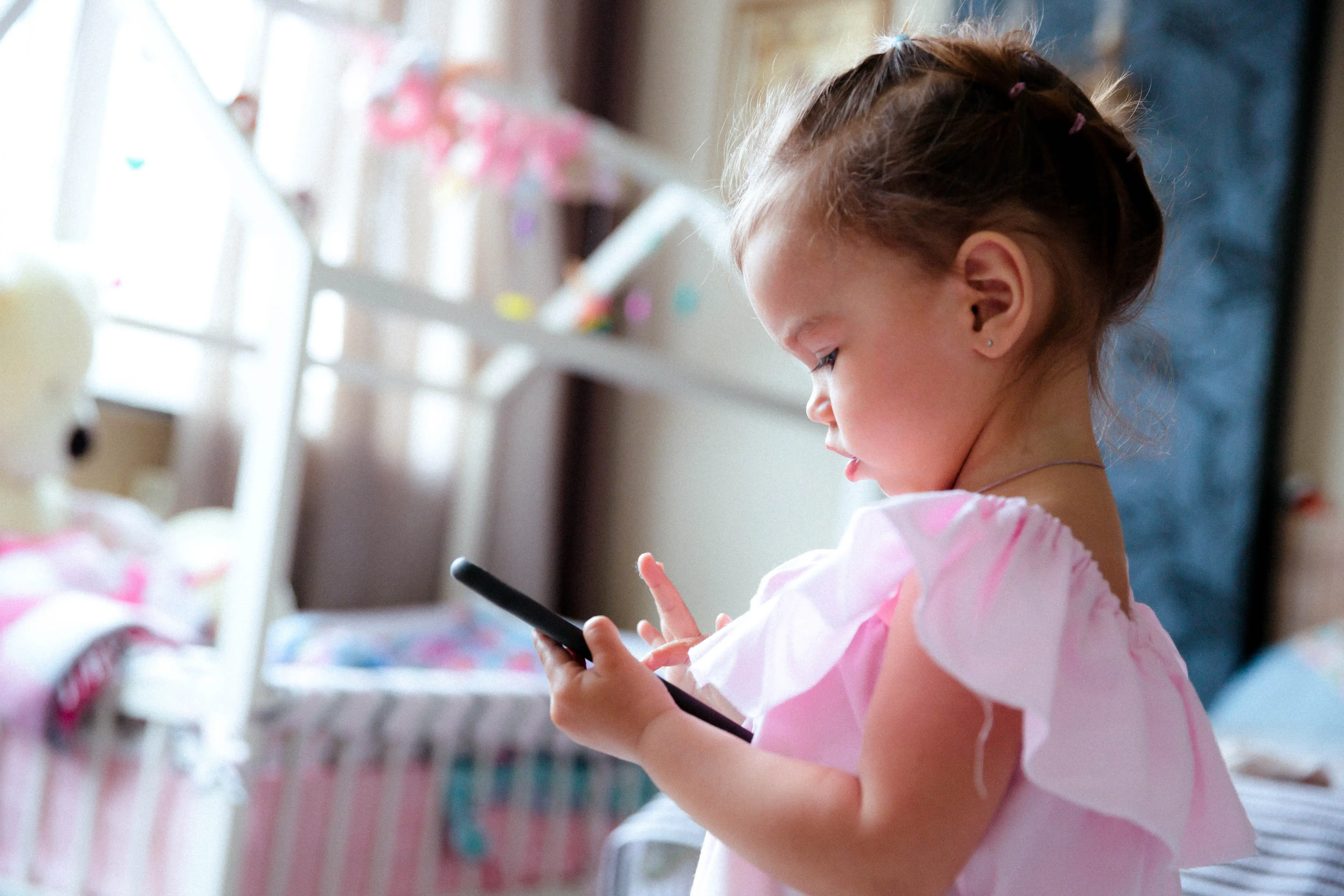 A young girl concentrating on a device indoors